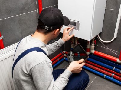The technician checking the heating system in the boiler room with tablet in hand